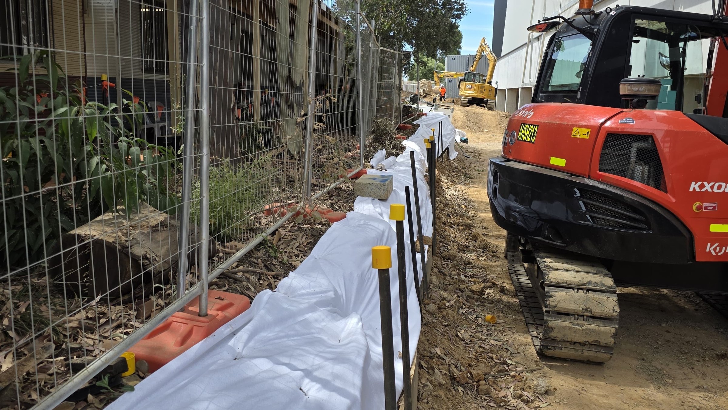 True Roots excavator and root protection along a fence line on a commercial site