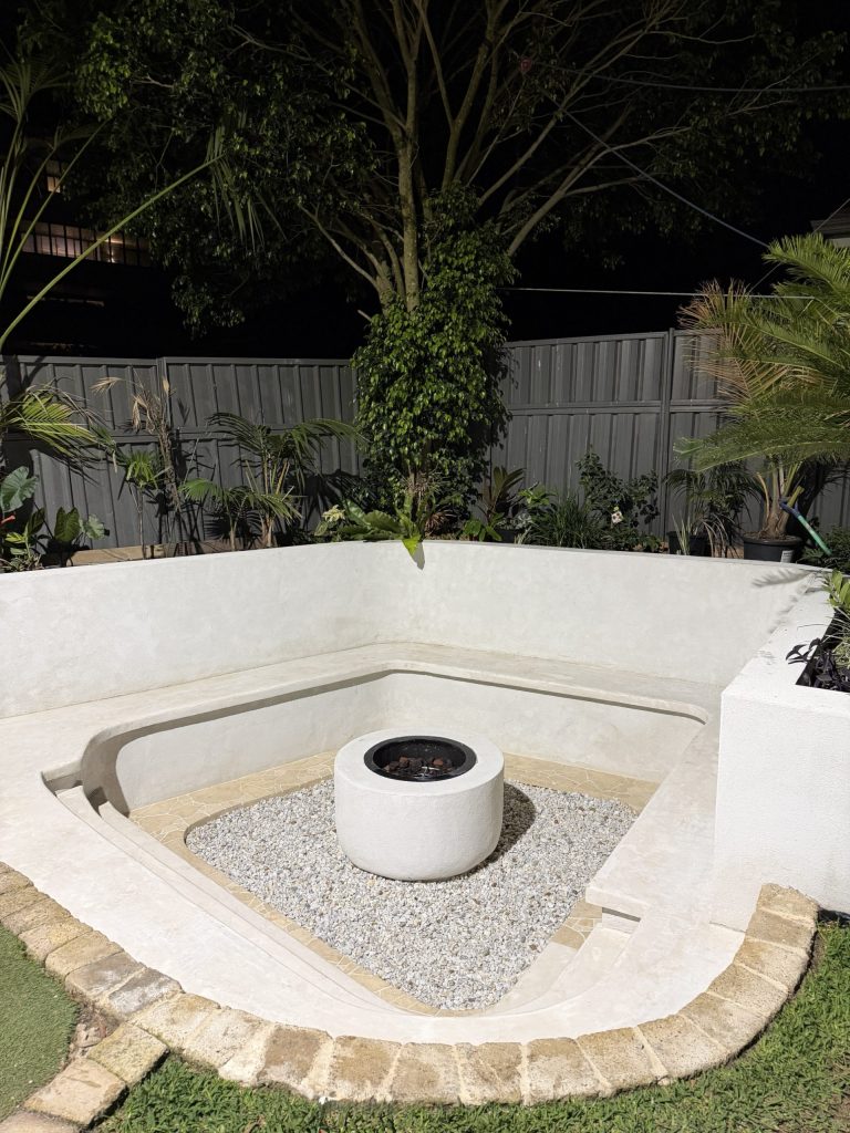 Sunken fire pit courtyard with rendered seating walls and planting built by True Roots landscapers in Miranda